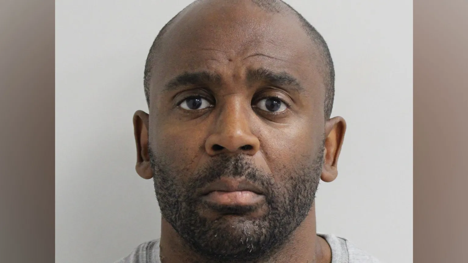 Metropolitan Police Clifton George, a shaven headed man, stares at the camera for a police custody photo 