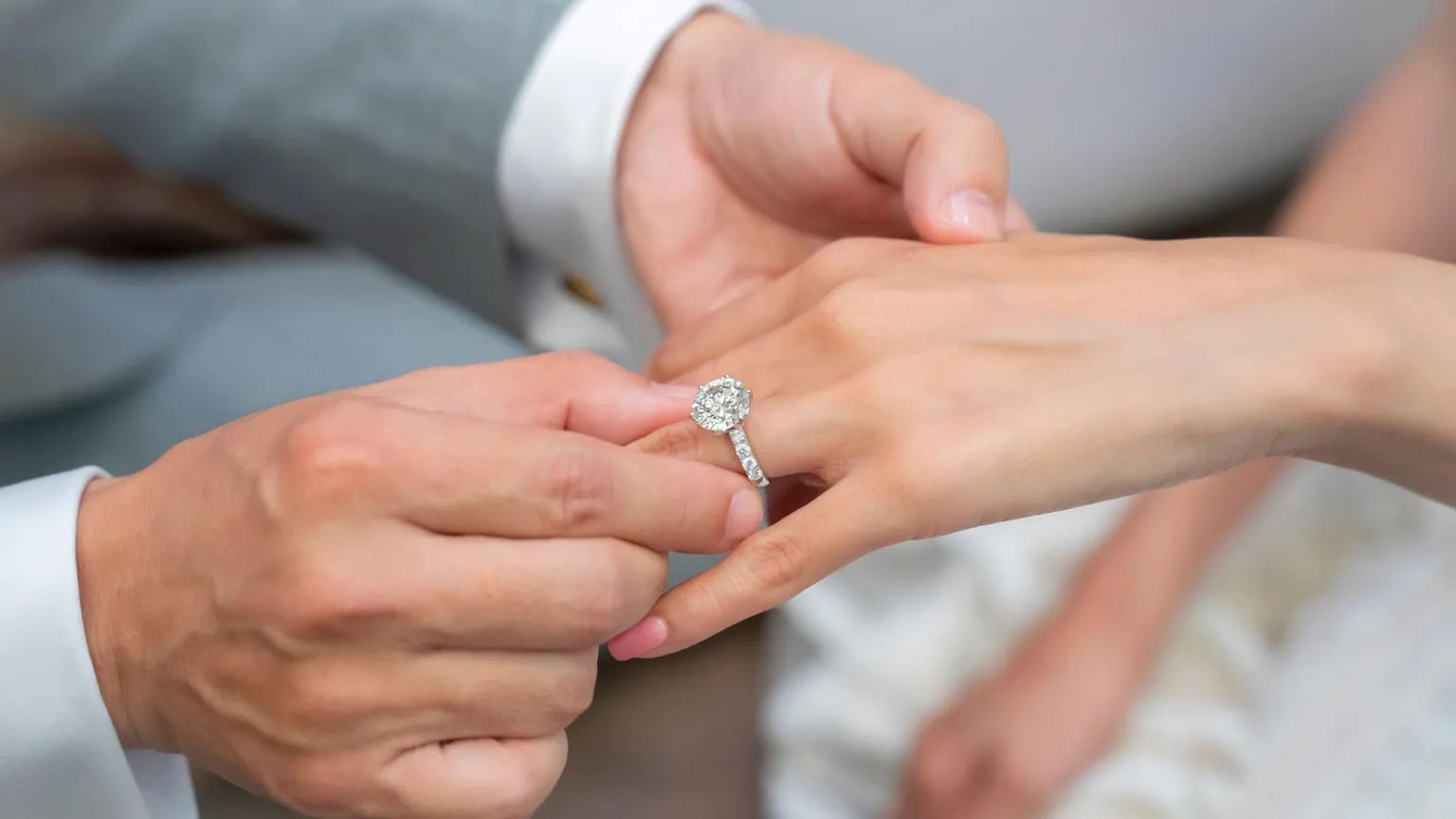  A man places an engagement ring with a lab-grown diamond onto his partner's hand