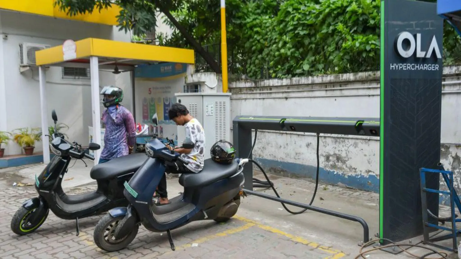 NurPhoto via People are seen charging their electric scooters at An OLA electric vehicle hyper charging station in Kolkata , India. 