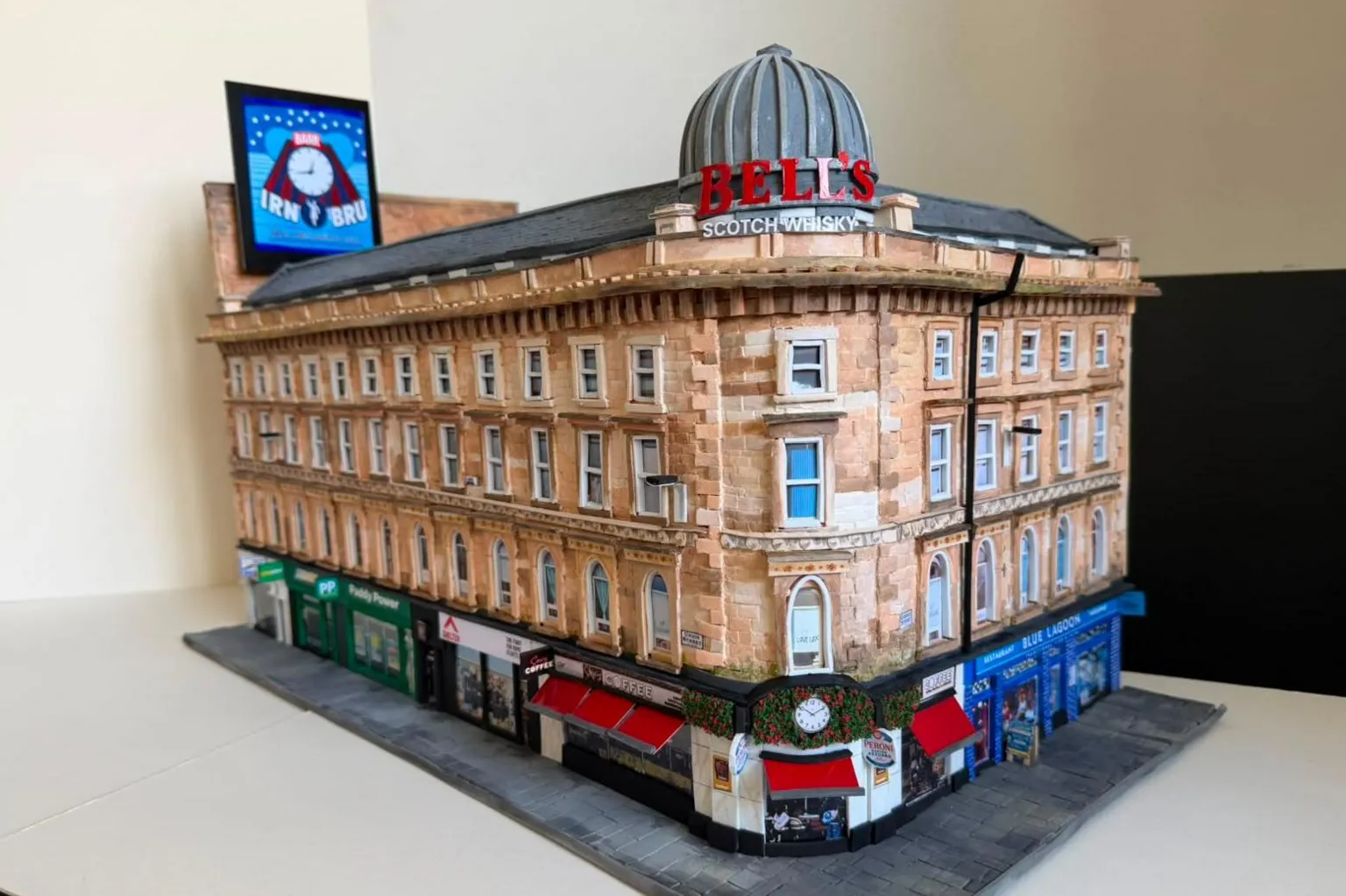 Karen Bones A cardboard model of Union Corner. It is a Victorian Building with colourful shop fronts on the ground floor.