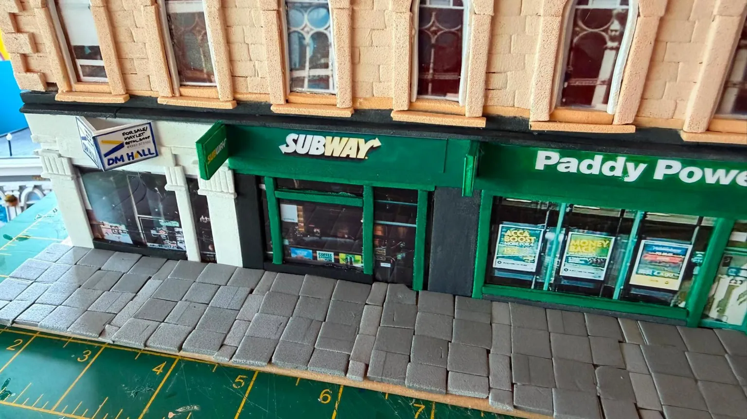 Karen Bones A cardboard model of Union Corner. It is a Victorian Building with colourful shop fronts on the ground floor.
