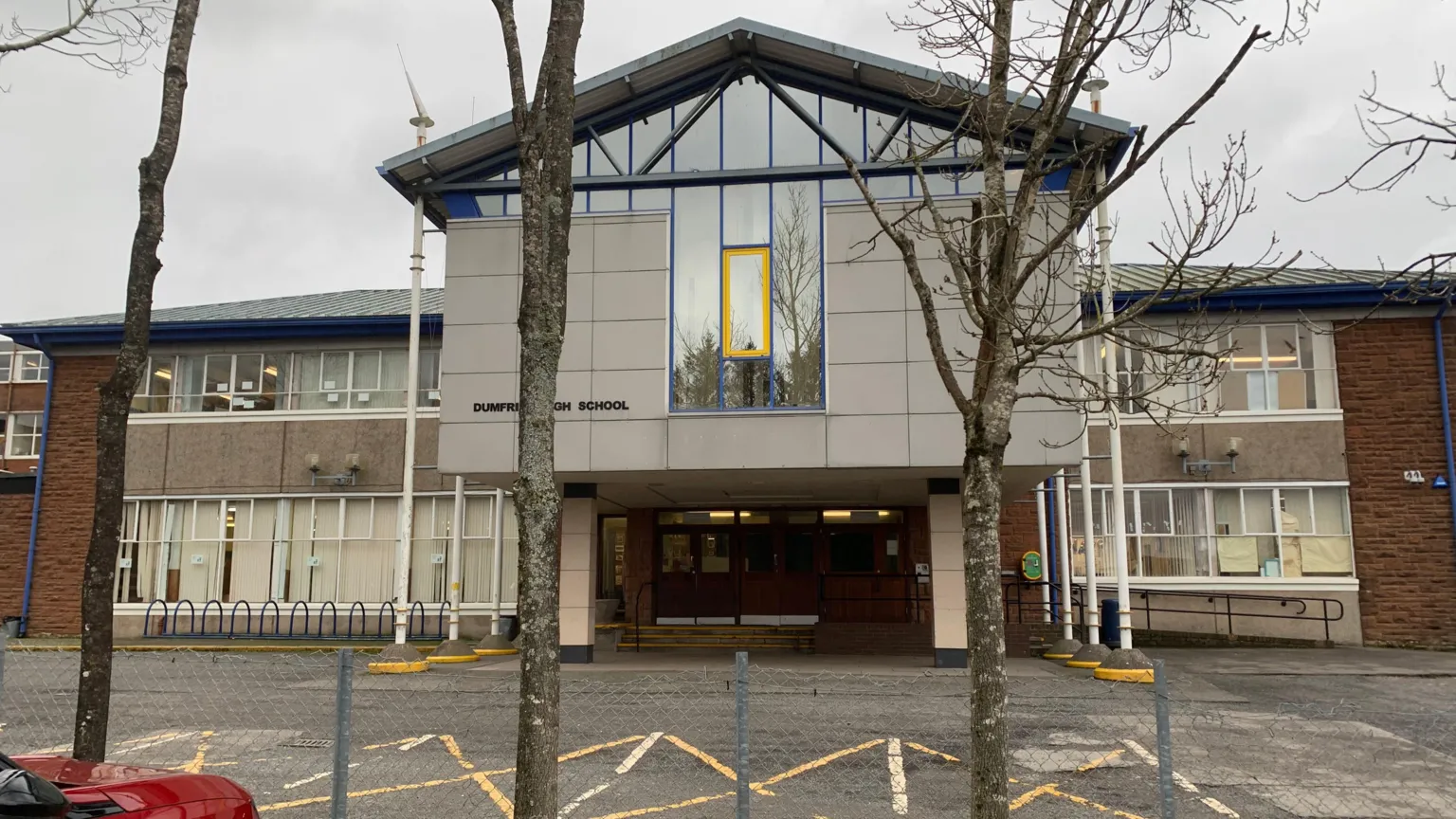 An external view of Dumfries High School, a 1960s building with a room on pillars above its entrance