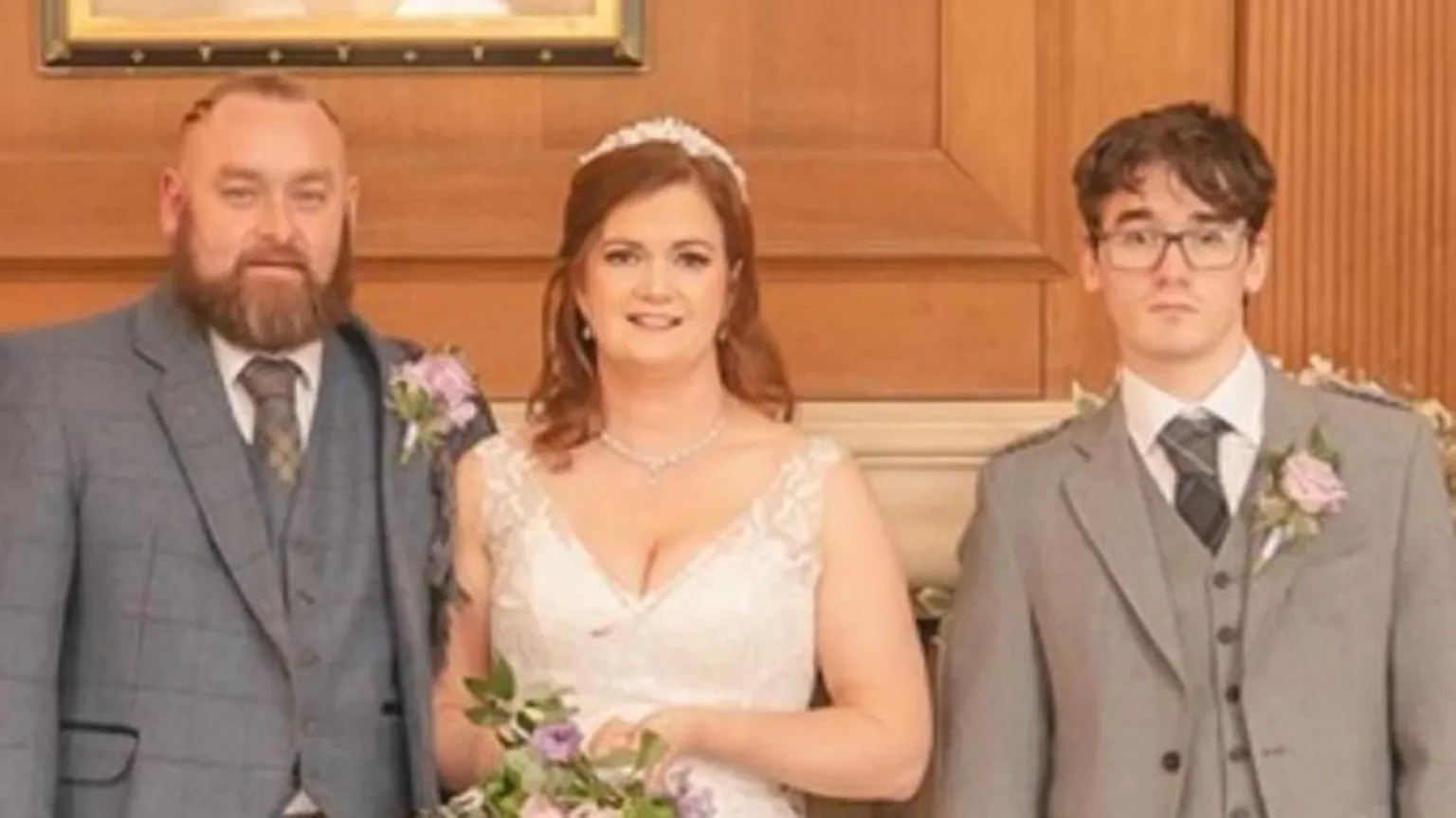 Duncan Ireland Photography A wedding photo. The groom with a beard and grey suit in on the left. The bride is in the middle, with a younger man in a grey suit on the right.