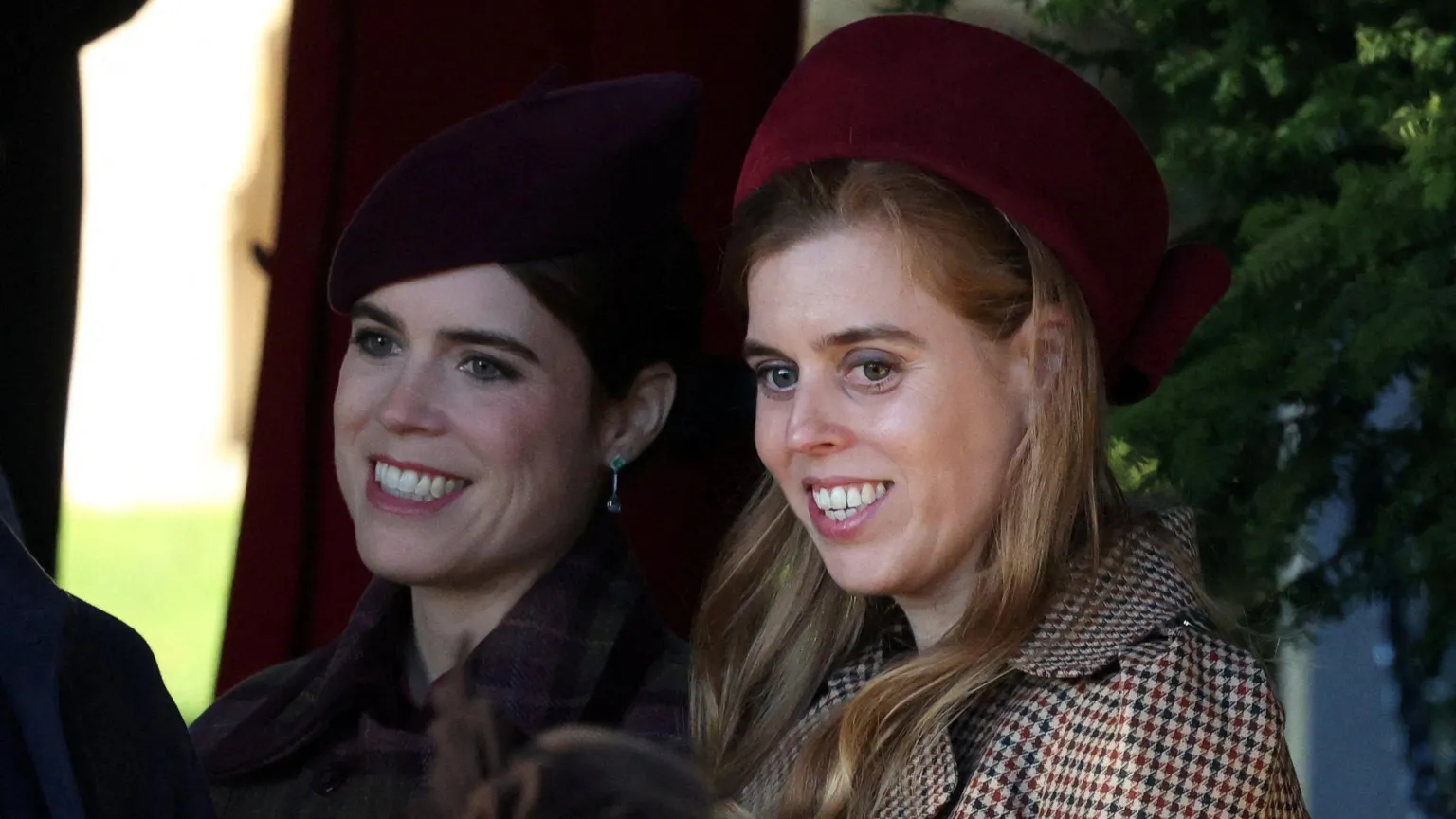  Britain's Princess Beatrice and Princess Eugenie smile. They are wearing hats and coats