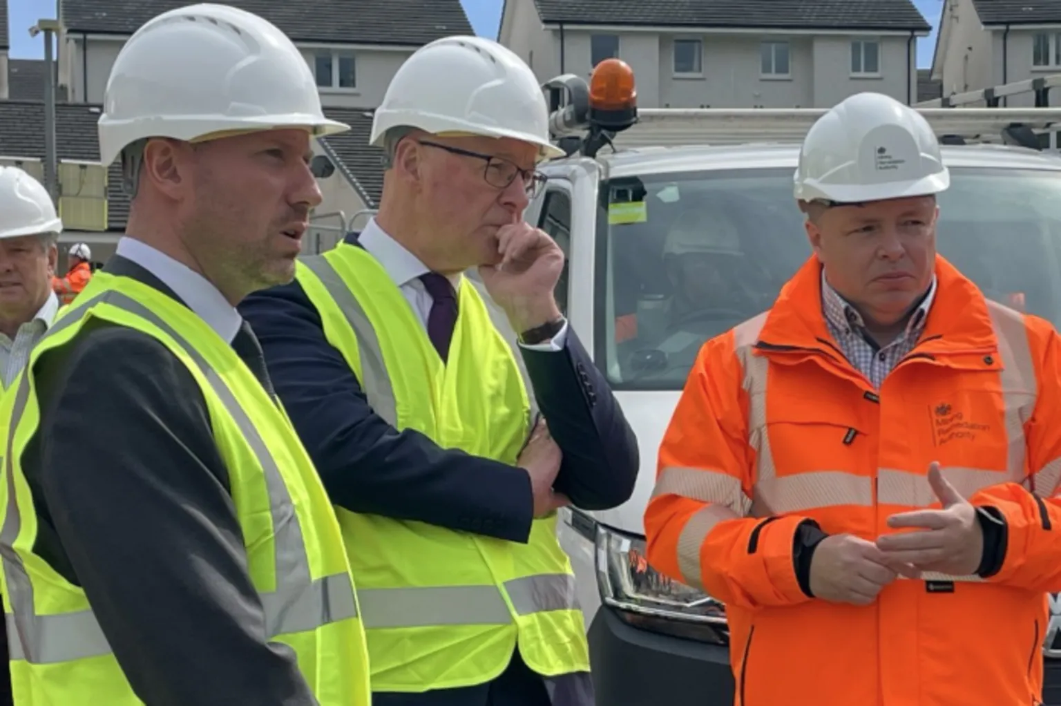 Two men in yellow hi vis and a man in orange hi vis in a residential street