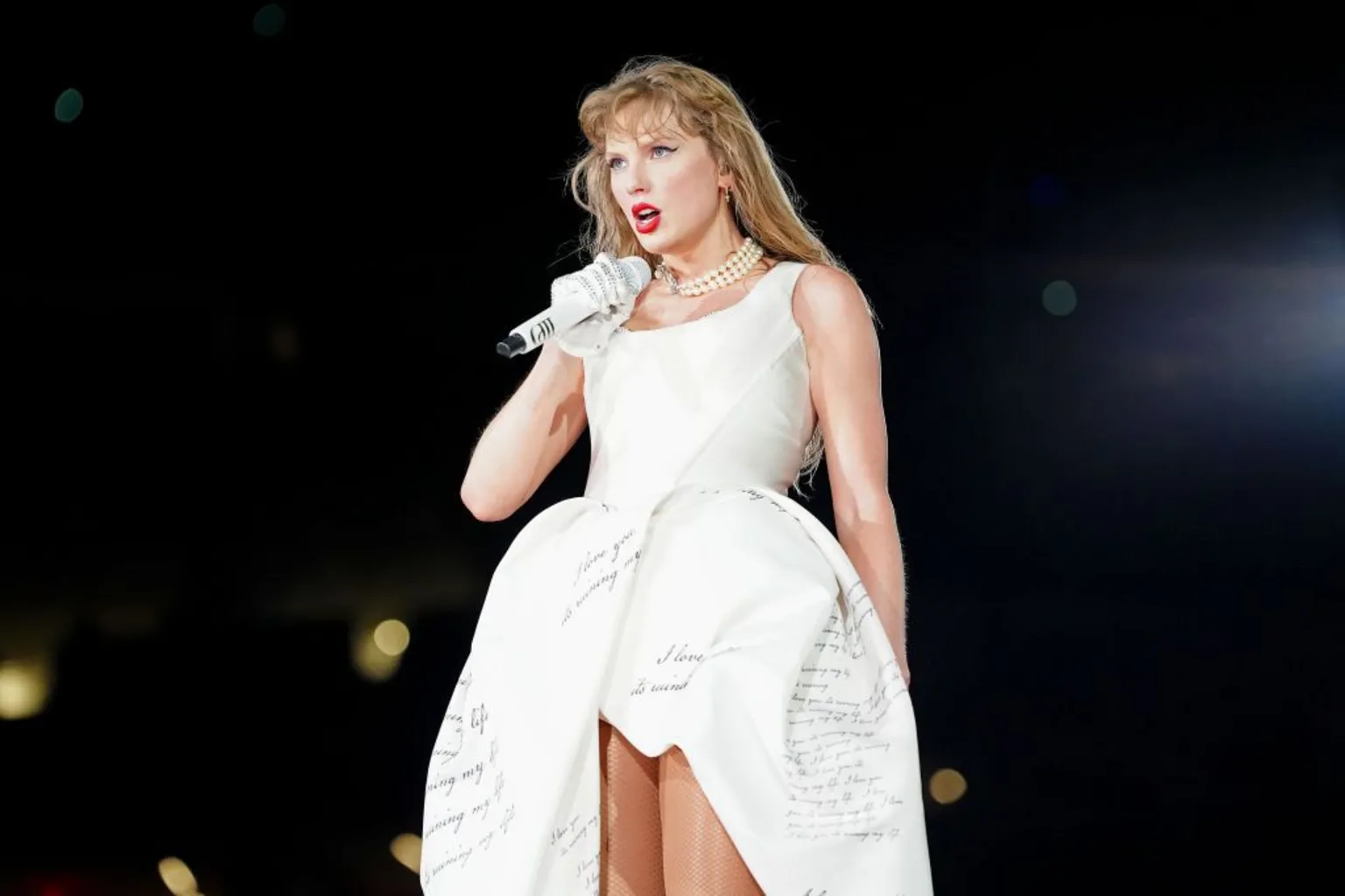  Taylor Swift wears a white gown with cursive writing printed on it as she performs onstage during 