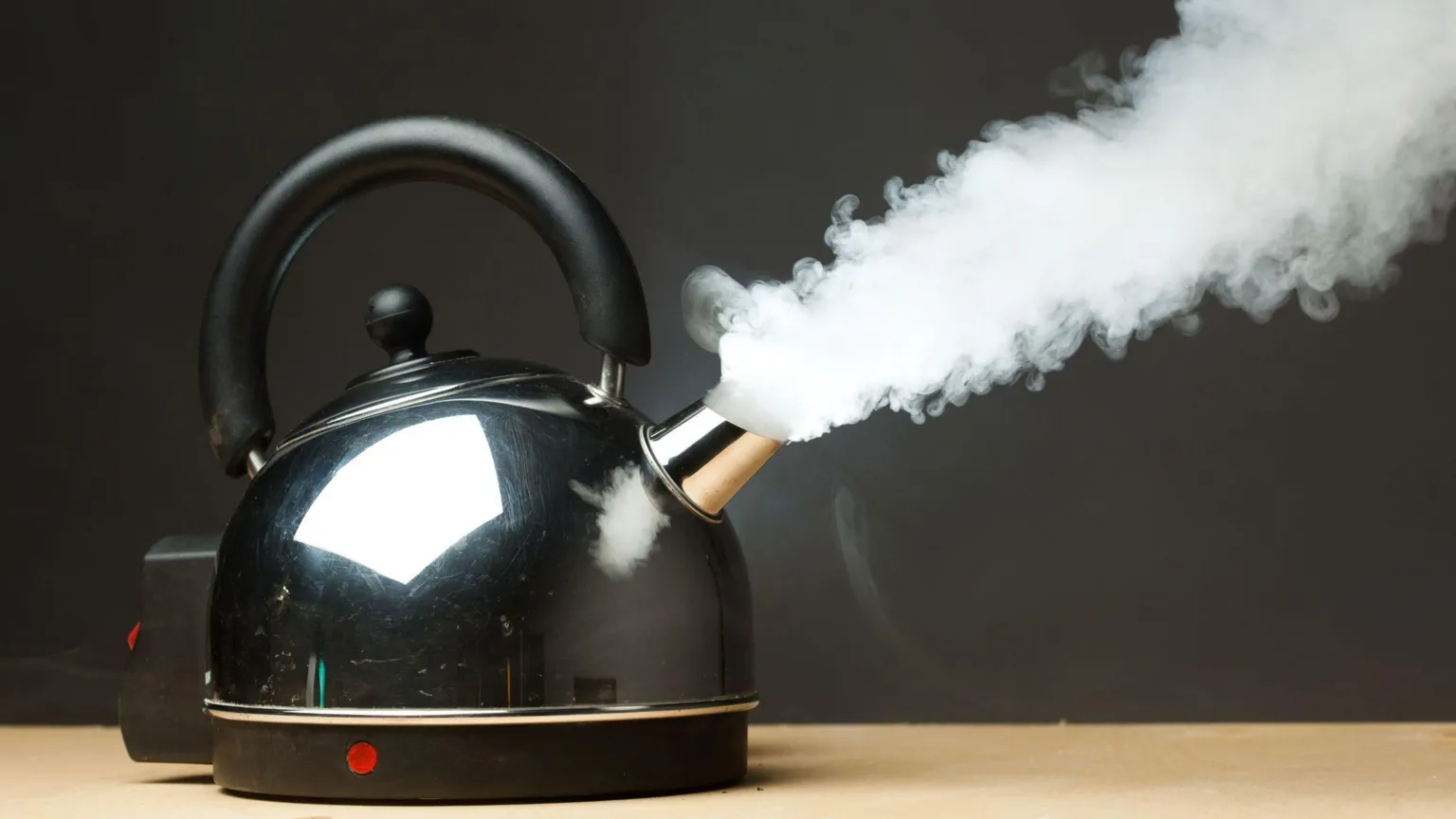  Dense steam emerges from the spout of a silver kettle as it boils.