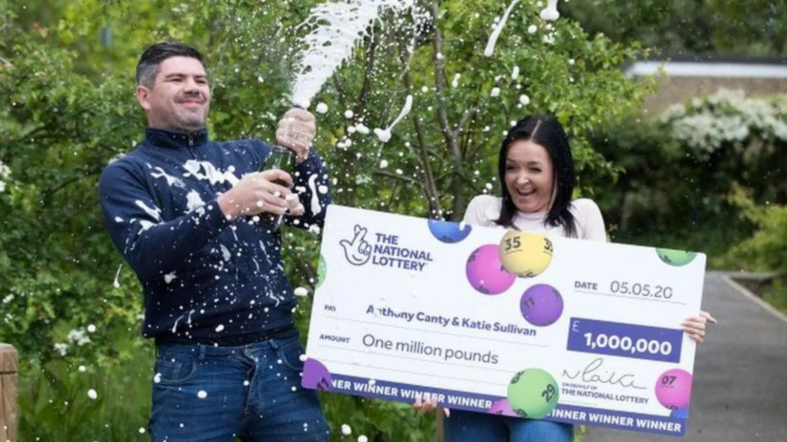  Canty sprays champagne from a bottle while Sullivan laughs and holds the cheque.