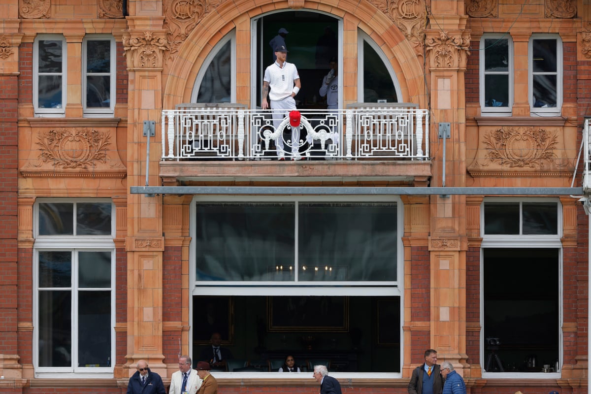 A wide shot of the Lord's home players' dressing room shows the England men's Test captain Ben Stokes, in his whites, looking out from the balcony during a rain break on day 3 of the Test match against New Zealand.