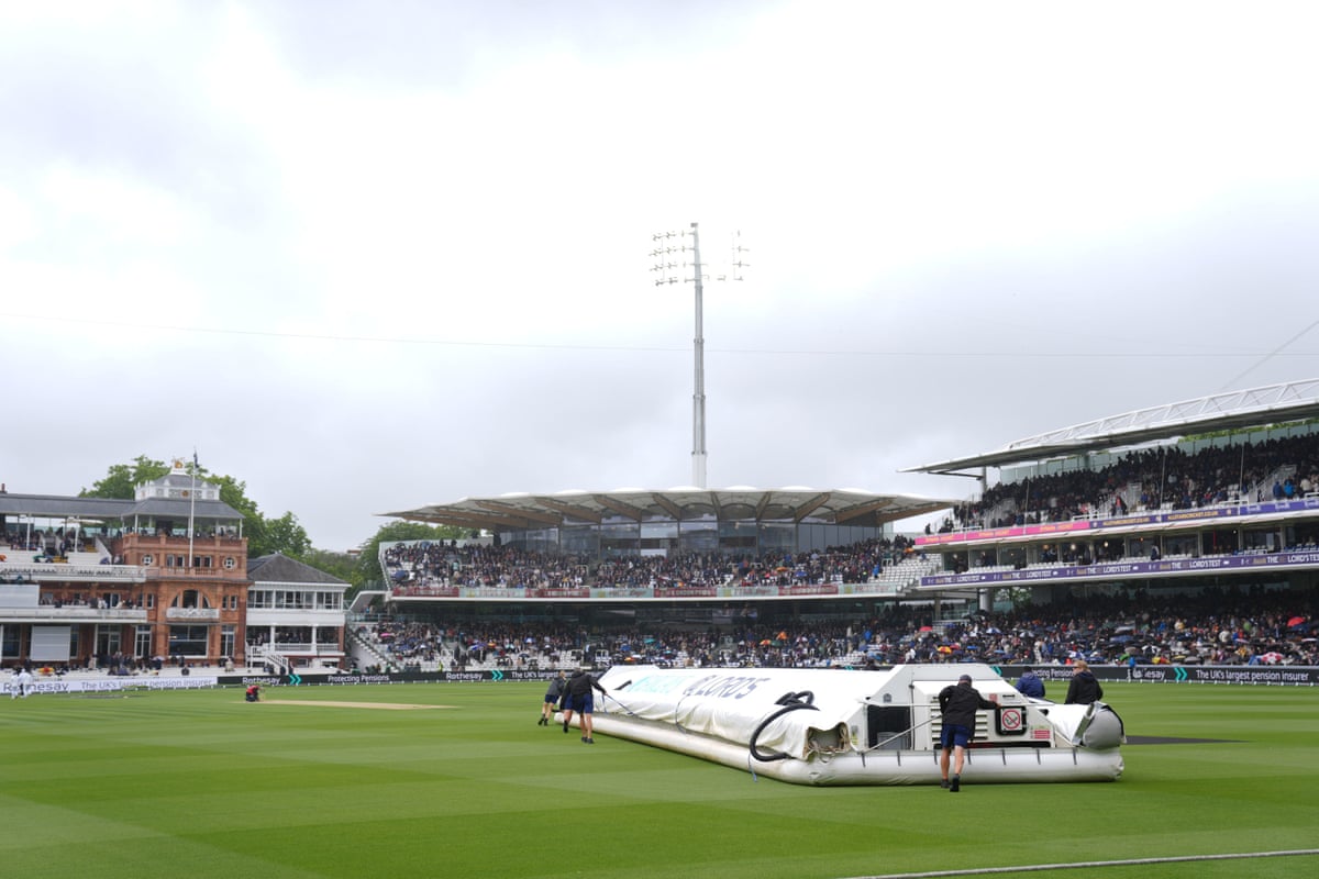 Groundsmen pull rain covers onto the playing surface at Lord's