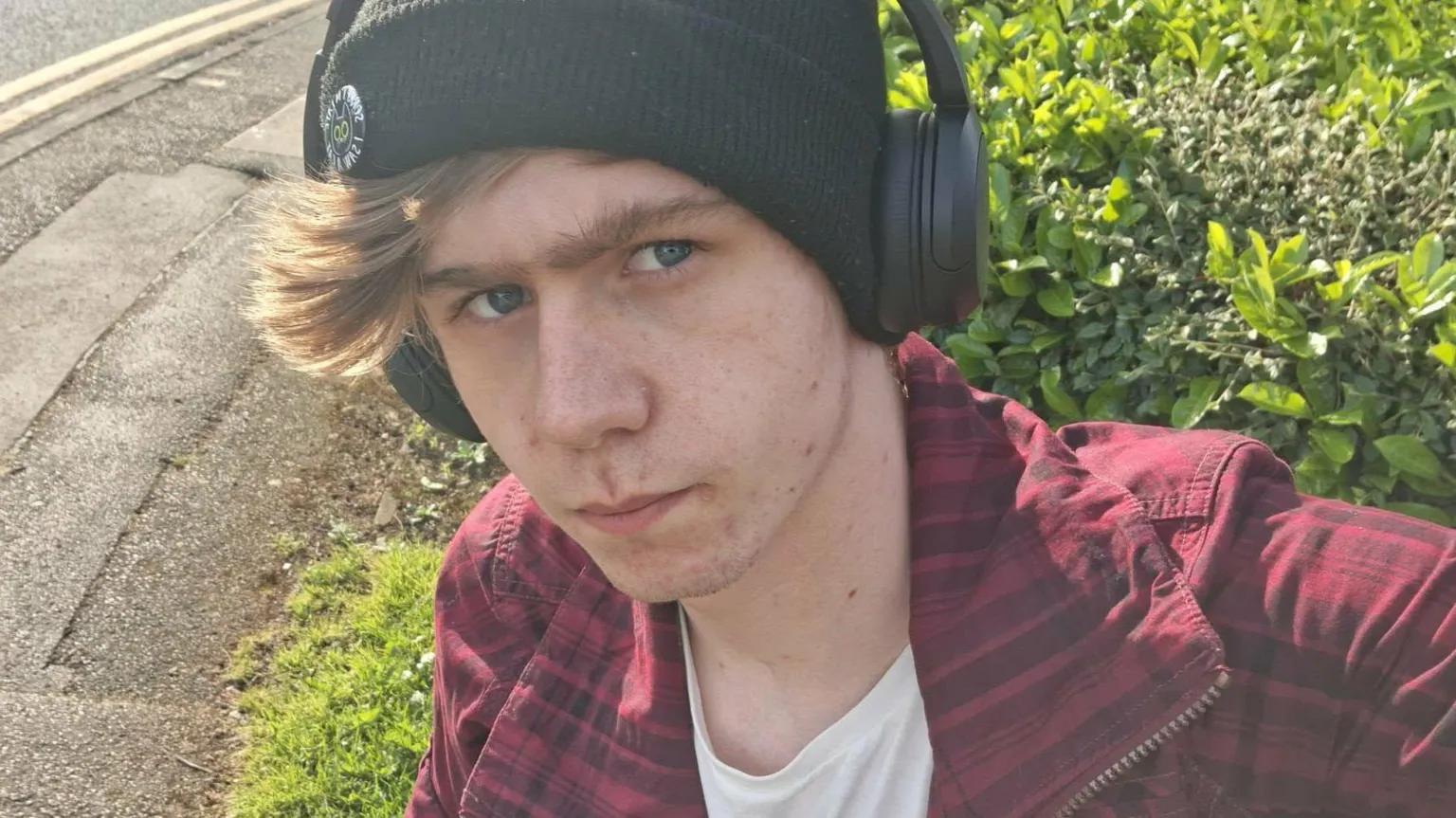 Joshua Clover is wearing headphones with a black beanie. He has on a red jacket.