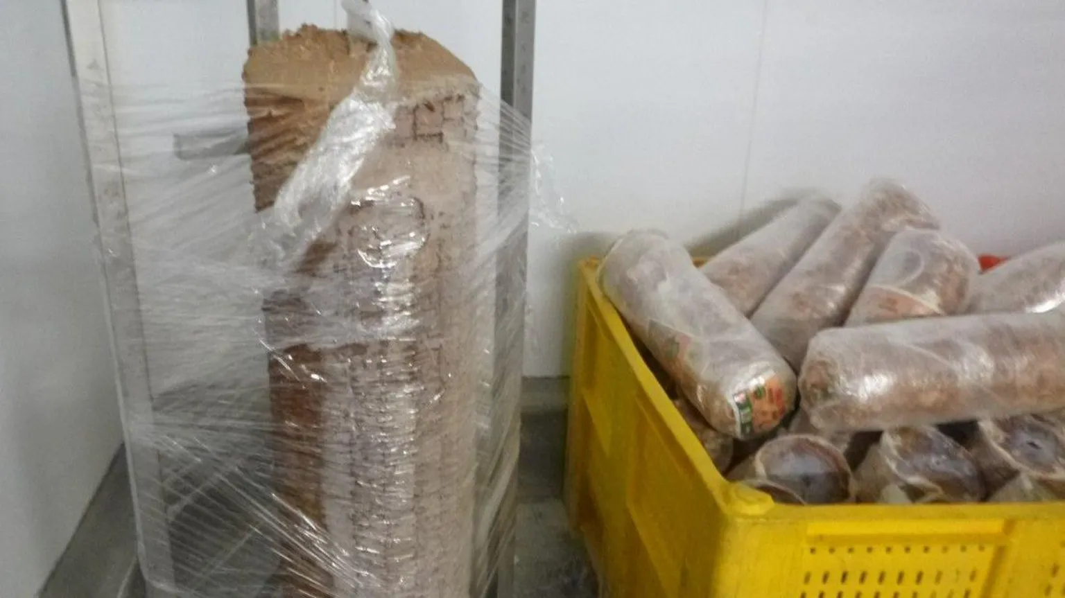 Media Wales Roll of kebab meat on large spit wrapped in plastic with more rolls packed and in a yellow crate to the right