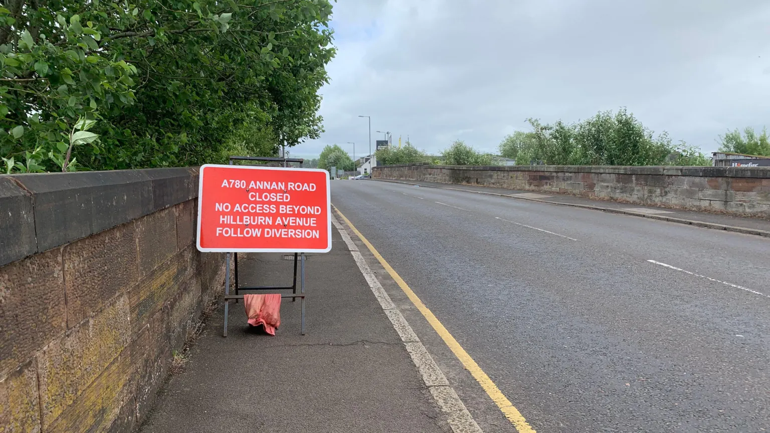 A road closure sign on the pavement next to an empty road