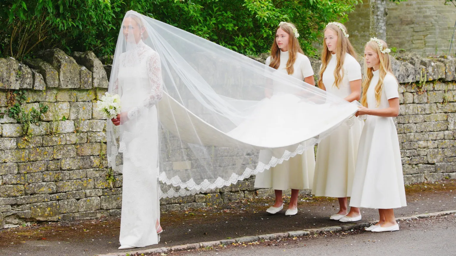  Bridesmaids hold veil outside church