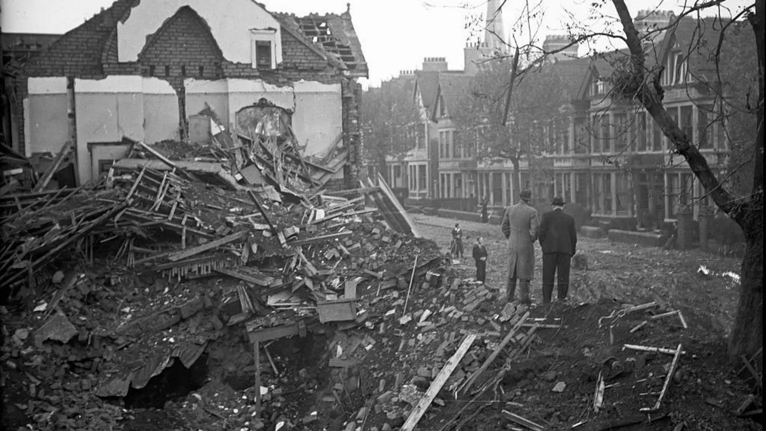 Mirrorpix via Destroyed houses in Cardiff. Two men are standing on the rubble. The image is black and white