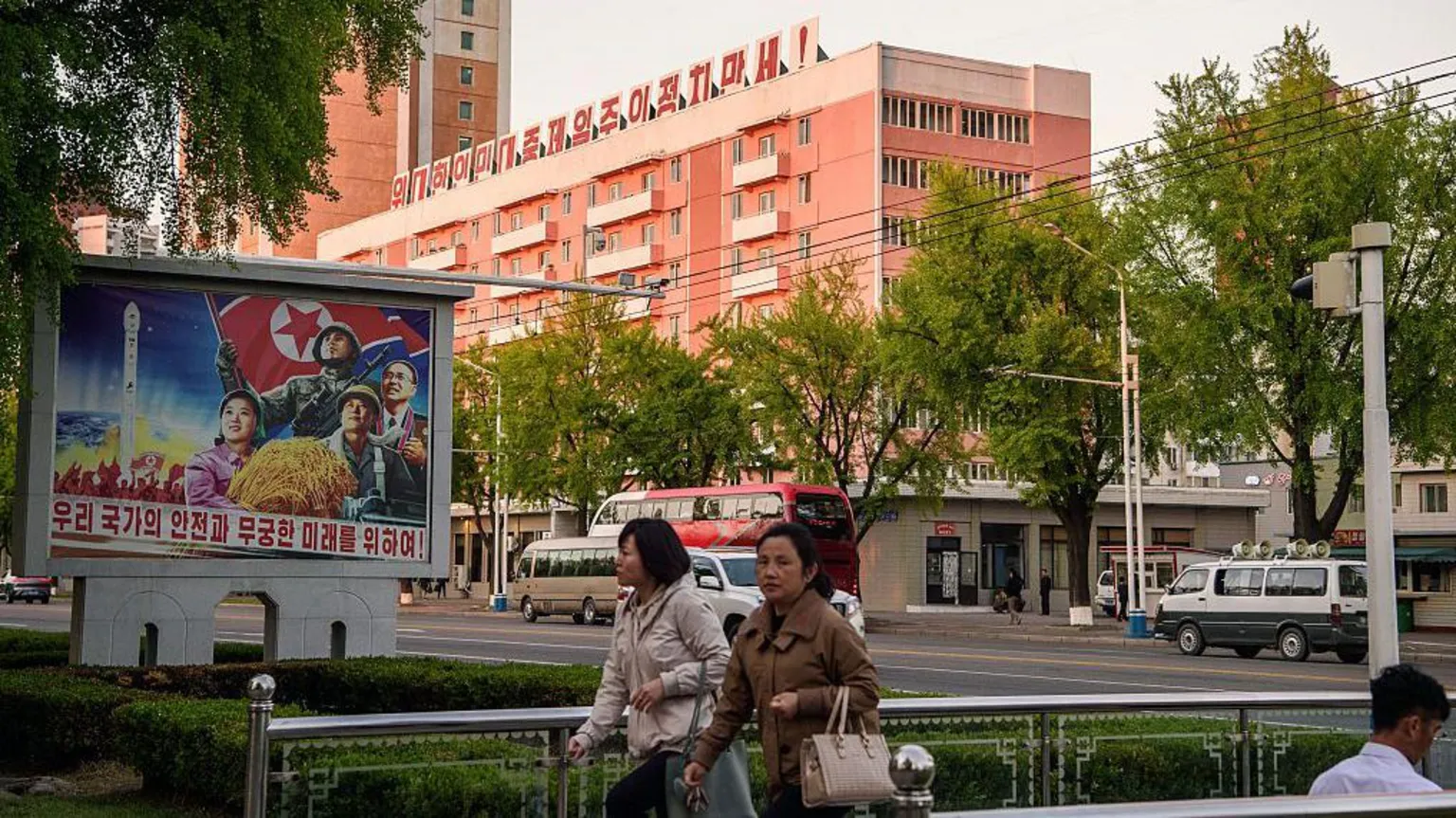 AFP via Pedestrians walk past a mural (L) that reads