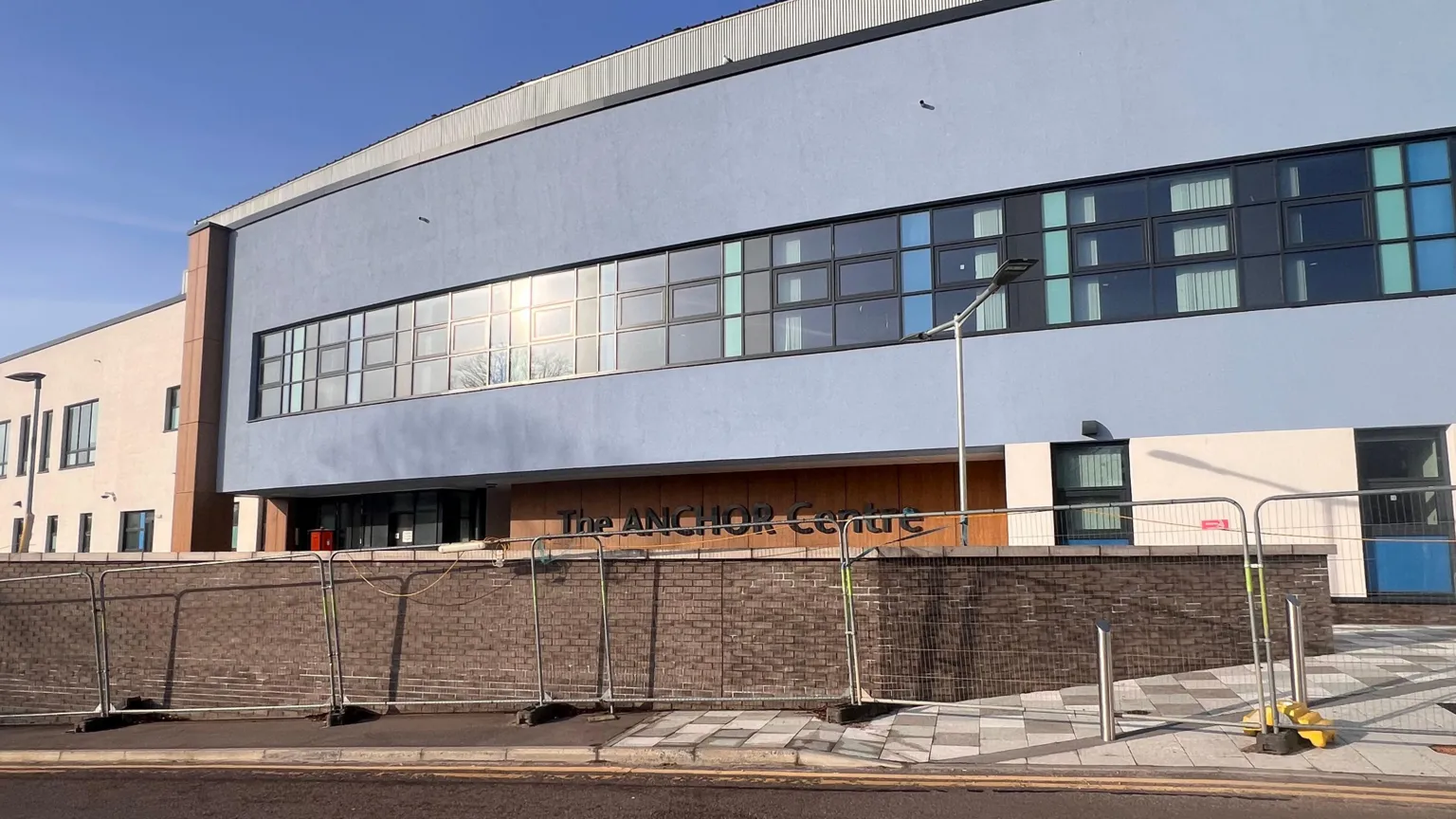 External view of the Anchor Centre in Aberdeen. It is a modern building and has temporary metal fencing around its perimeter.