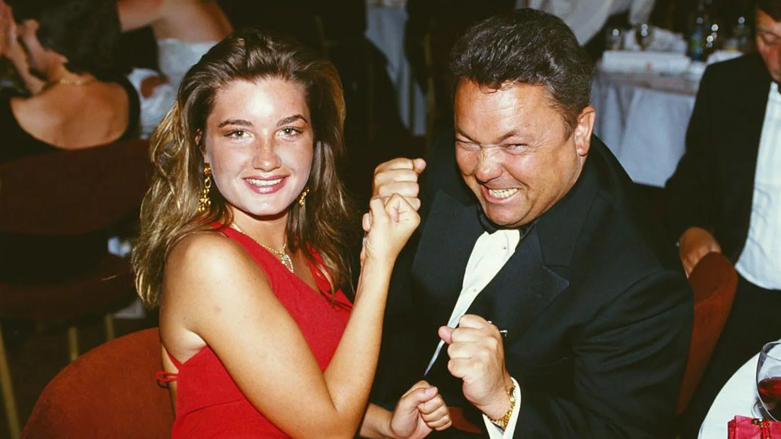 Karren Brady, wearing a red dress and and David Sullivan, wearing a black suit and bow tie, pose for a picture at a function in 1993.