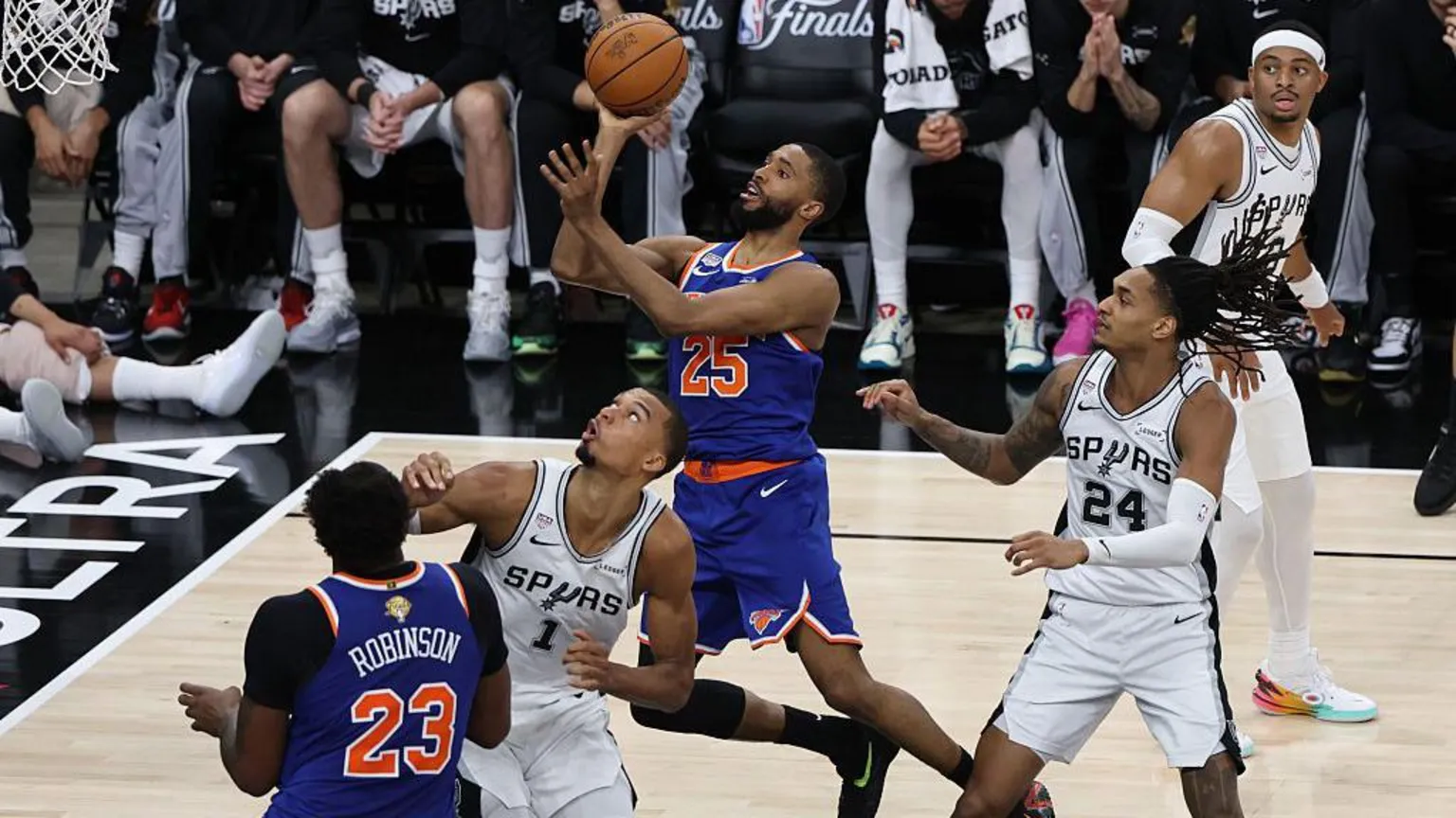 NBAE via A Knicks player leaps towards the basket with the ball in hand as opposing Spurs players surround him