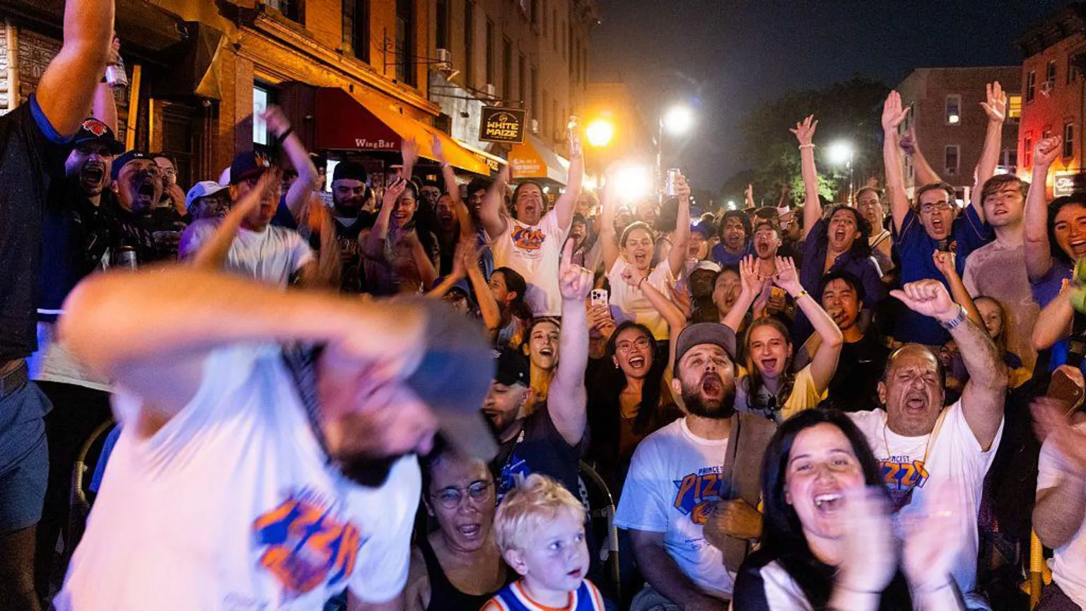 Corbis via Dozens of fans cheering and watching a basketball game in the street