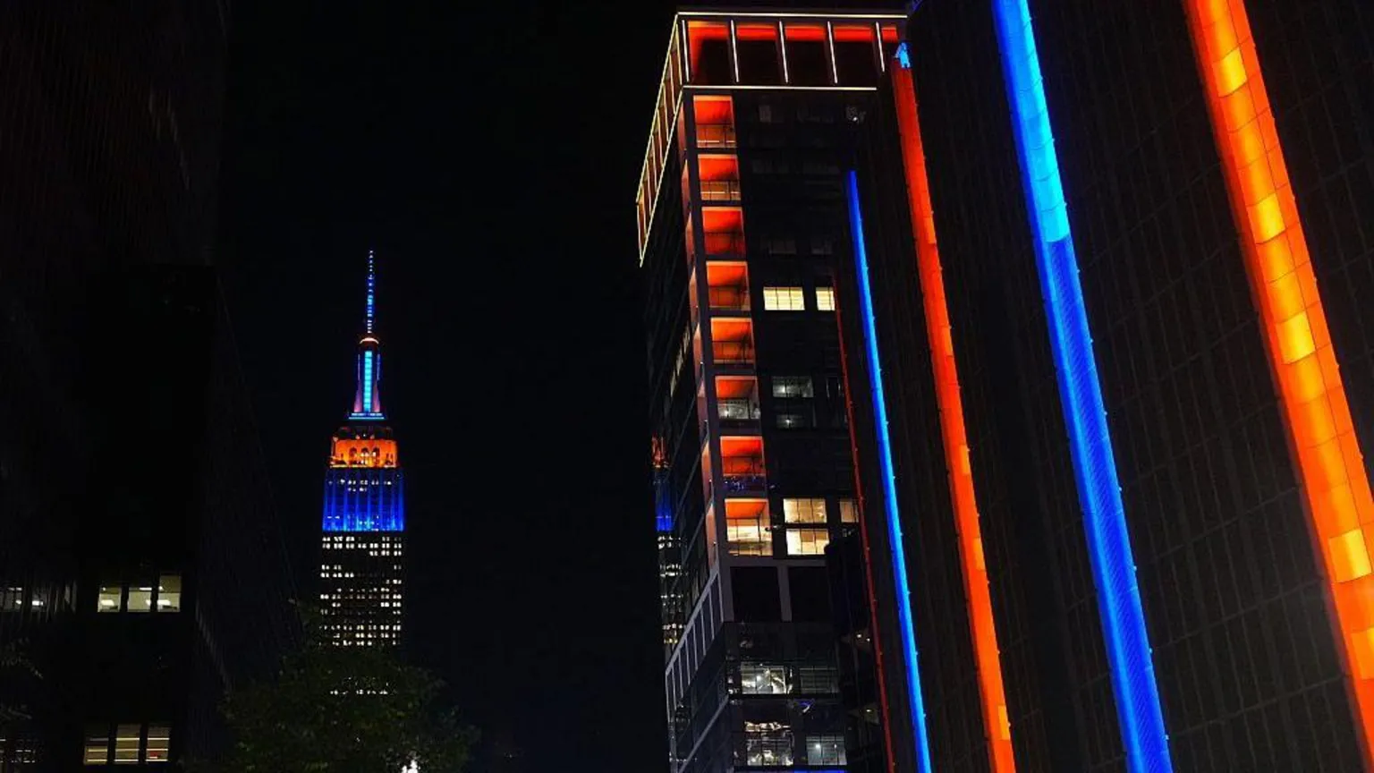 Anadolu via City skyscrapers lit up in orange and blue amid night sky