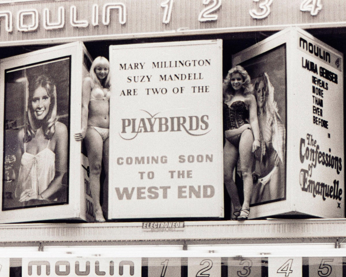 Mandell and Millington stand in underwear next to a sign above the cinema’s entrance advertising the film The Playbirds