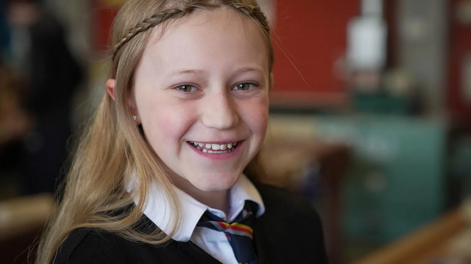 Olivia smiling at the camera in a school classroom