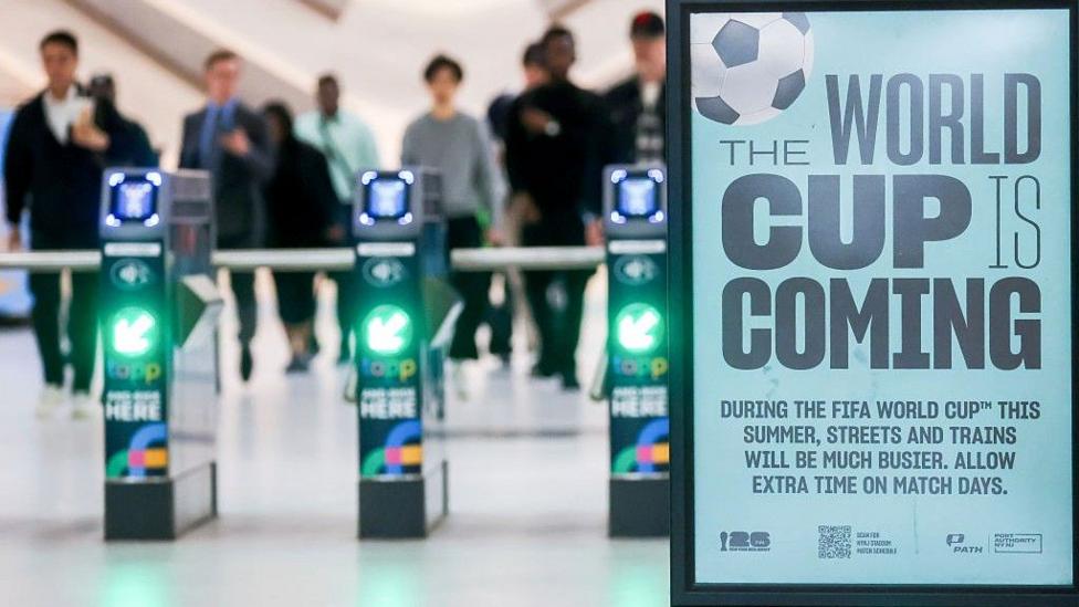 An image of turnstiles with the sign 'The World Cup is coming'