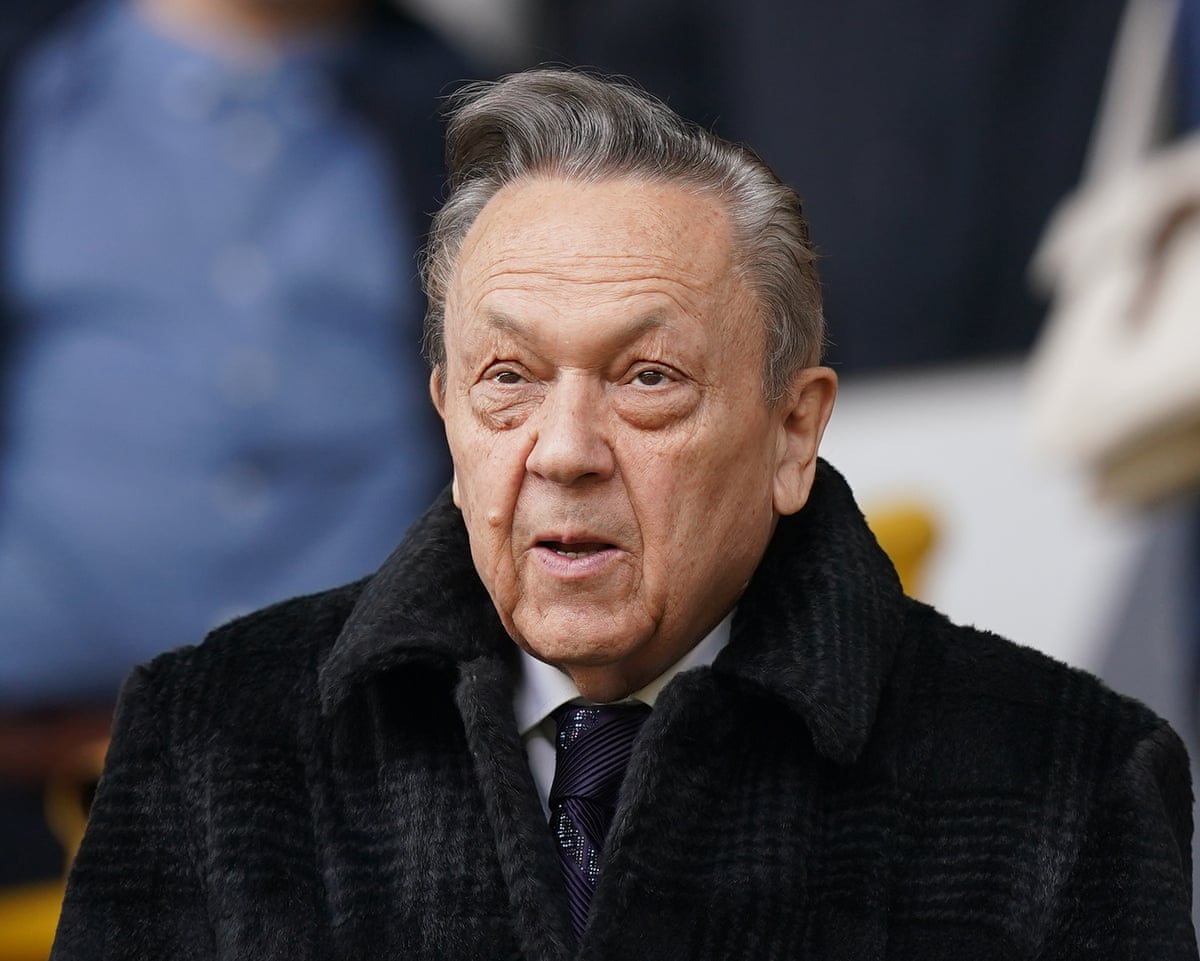 Sullivan in a black fur-collared coat and tie