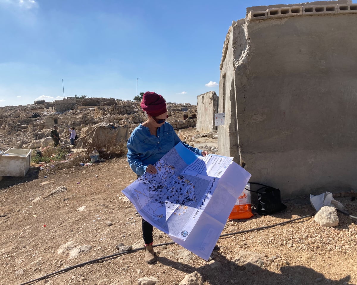 A woman standing in a deserted village looking at a map