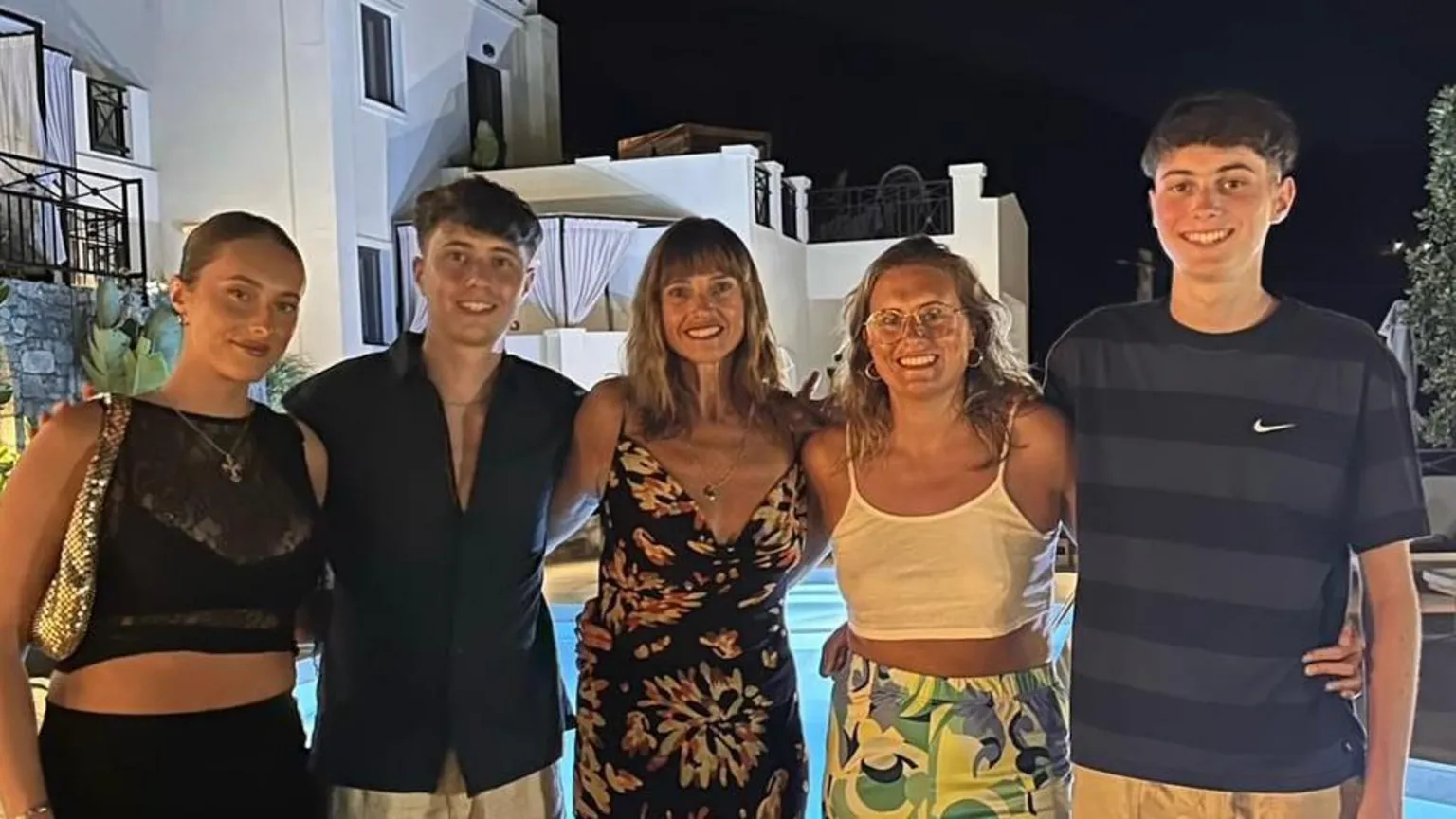 Semple Family Lisa Semple and her four grown-up children. They are standing in front of a swimming pool and white building on holiday. The two sons are wearing dark-coloured tops while the two daughters and Lisa are wearing dresses, skirts and tops.