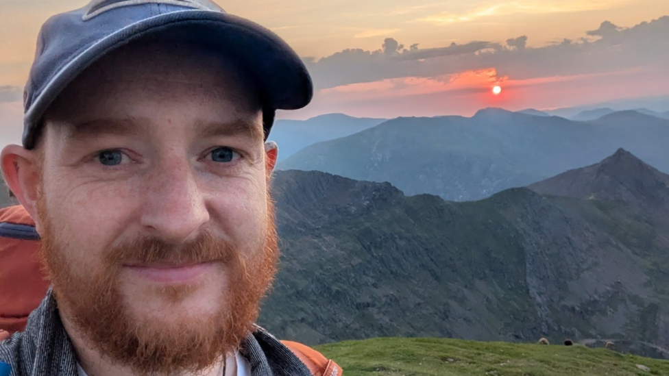 Llun Bryn Hughes ar ben mynydd