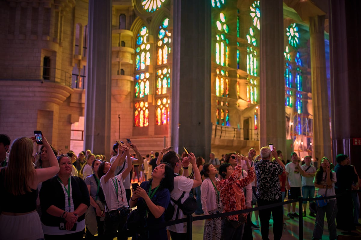 Tourists taking photos inside, lit by stained-glass windows
