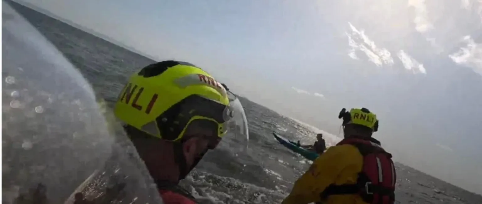 RNLI Barry Dock A picture from the rescue taken from the RNLI boat. Two crew members can be seen wearing RNLI helmets and lifejackets. In the background Marley can be seen on top of the kayak in the sea. 