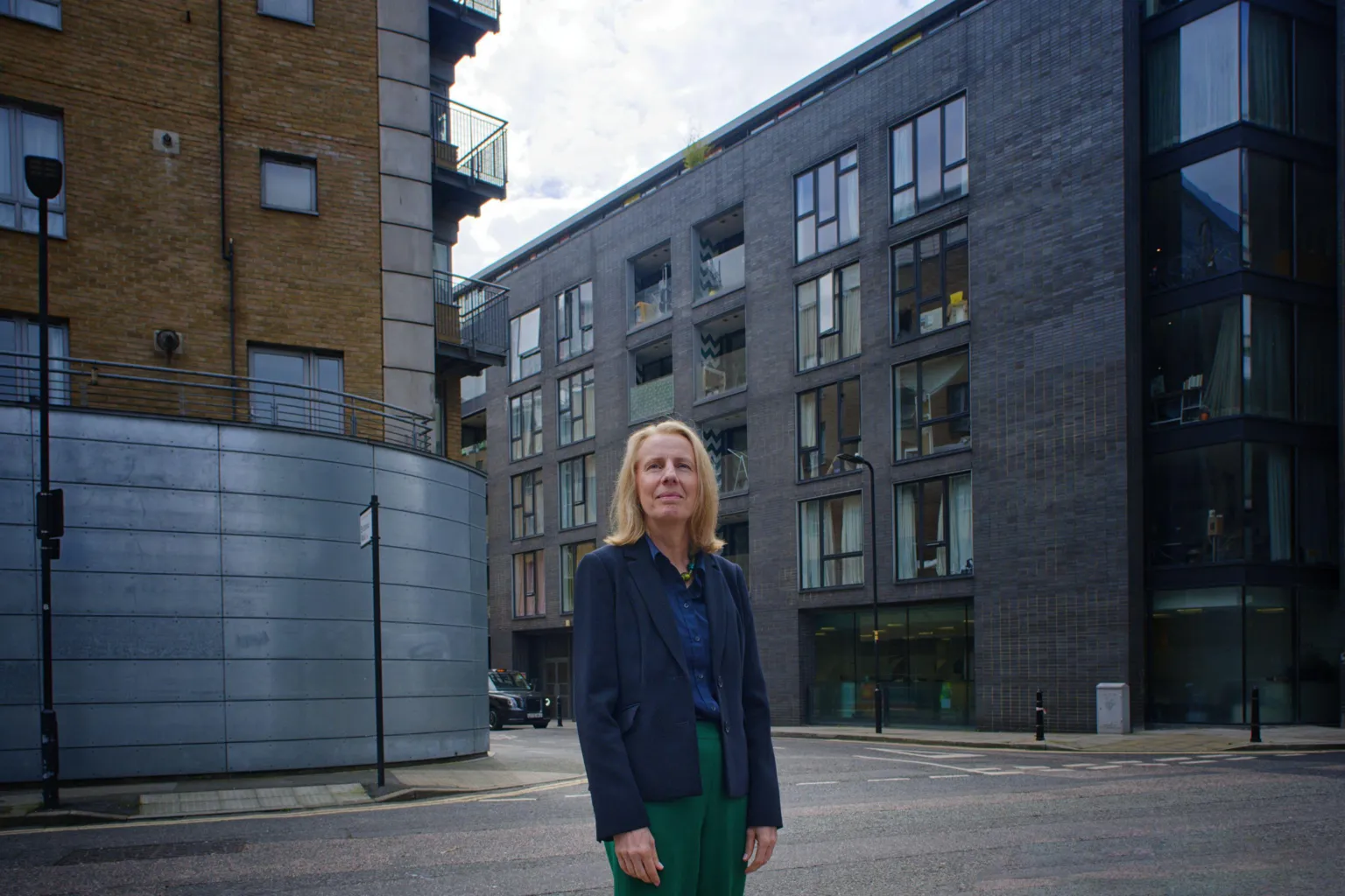 Sue Percy stands near the five-storey CIHT offices in central London. She wears green trousers and a dark blue blazer