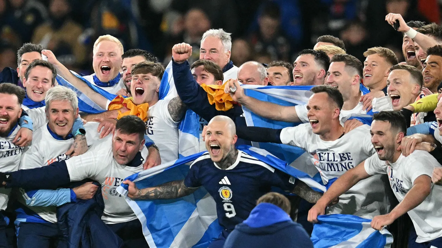  Scotland sqaud huddled and shouting with flags on their backs