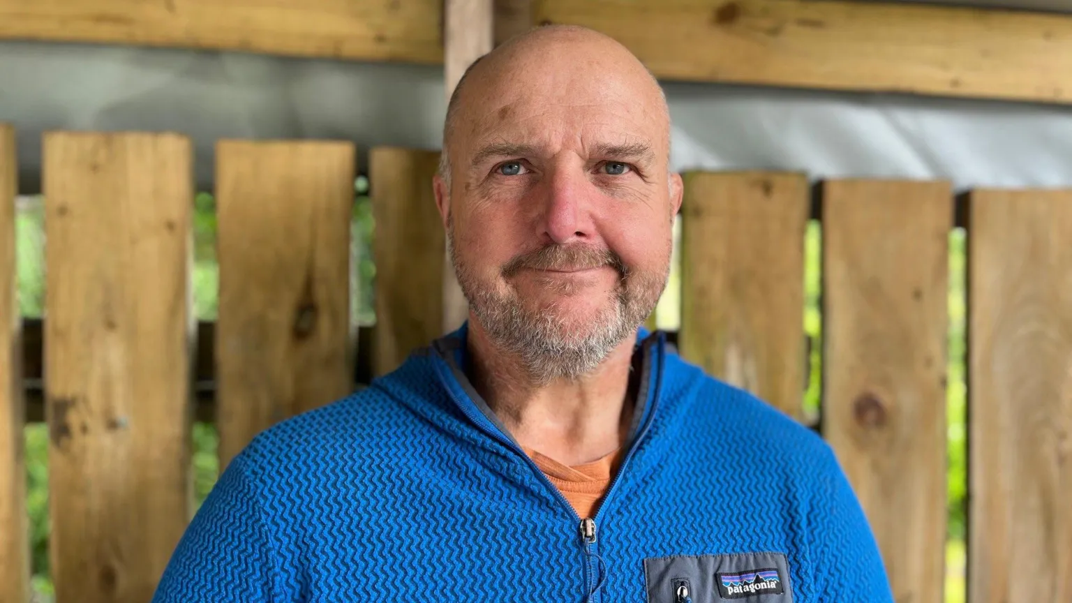 Andy Jones, smiling at the camera. He has a bald head and a short grey beard. He is wearing a blue sweat top.