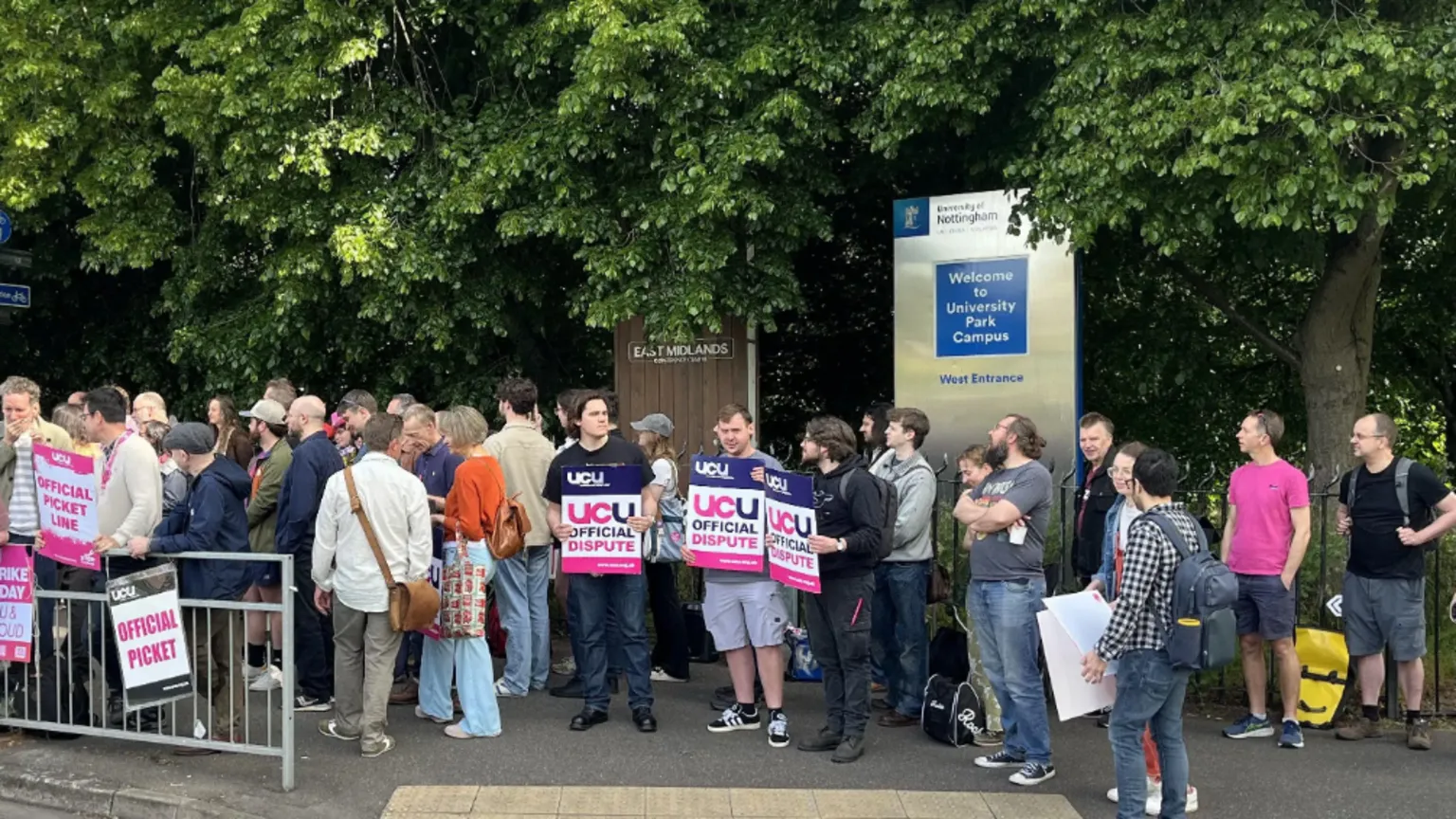A line of students holding placards next to a University of Nottingham sign