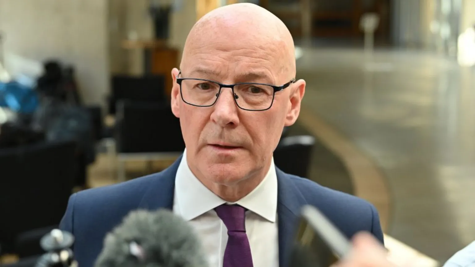  John Swinney speaks into microphones in the Scottish Parliament 