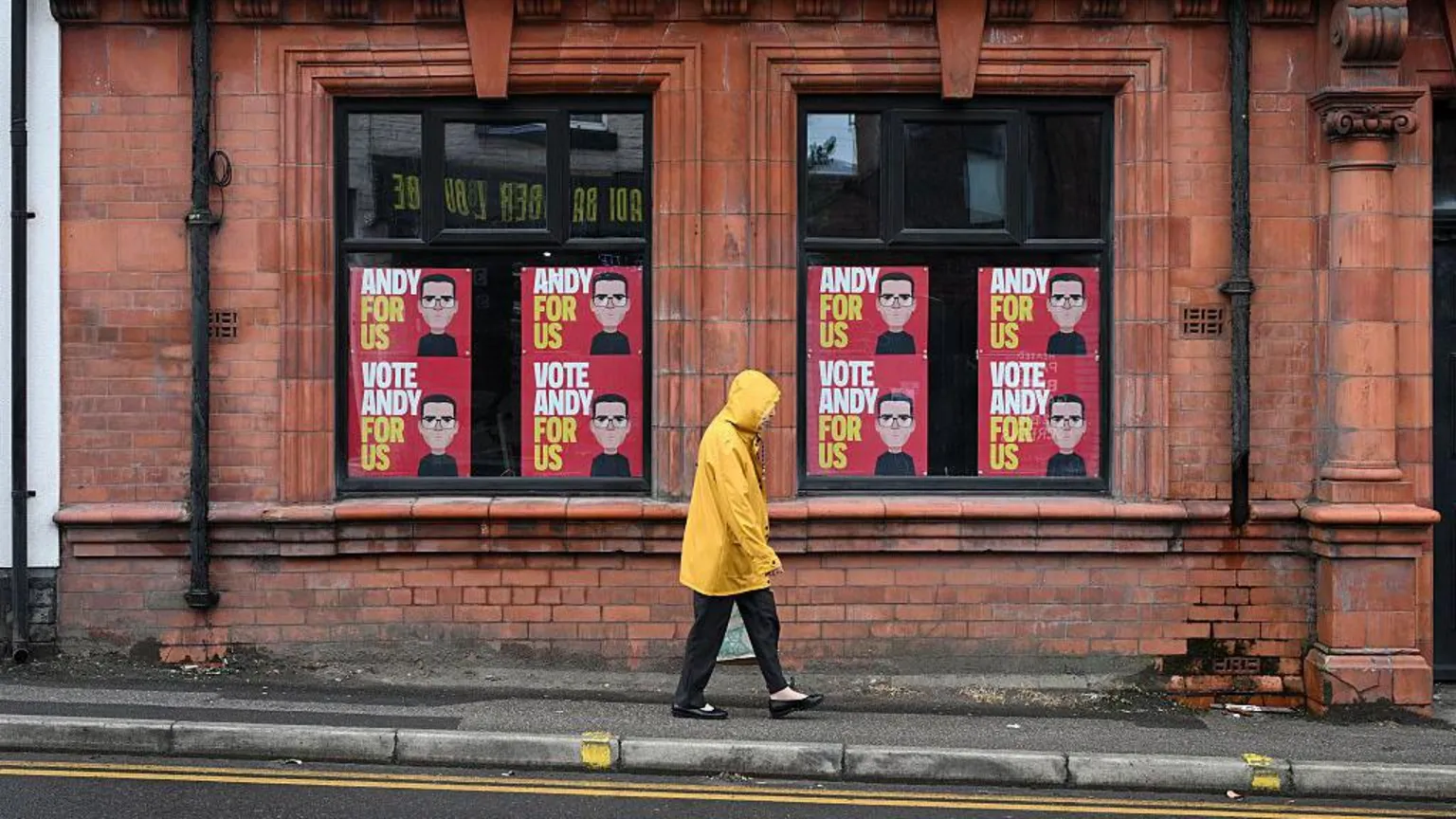  A man walking past Andy Burnham signs