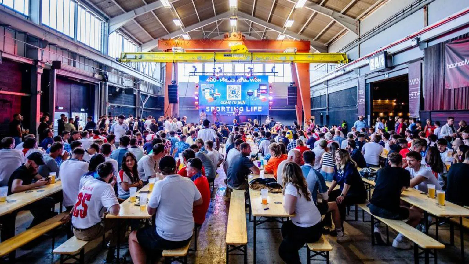 PROSPECT BUILDING A crowd of England fans sit around pub tables inside a large warehouse-style building