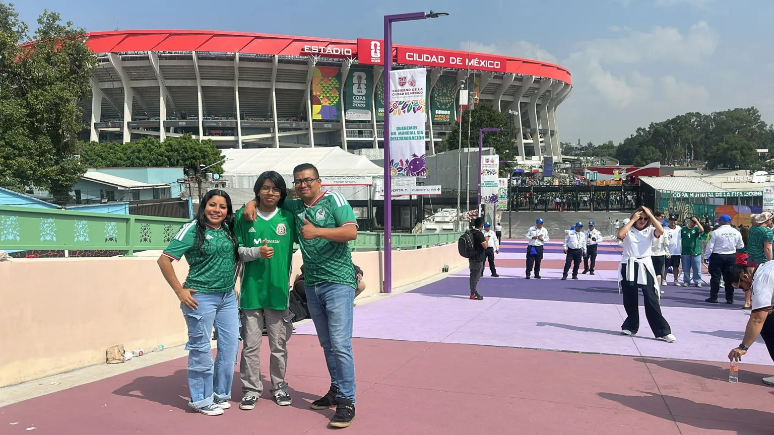 Will Grant / BBC Javier Pérez and his family, wearing Mexico jerseys as they stand in front of the Azteca stadium and give the thumbs up to the camera.