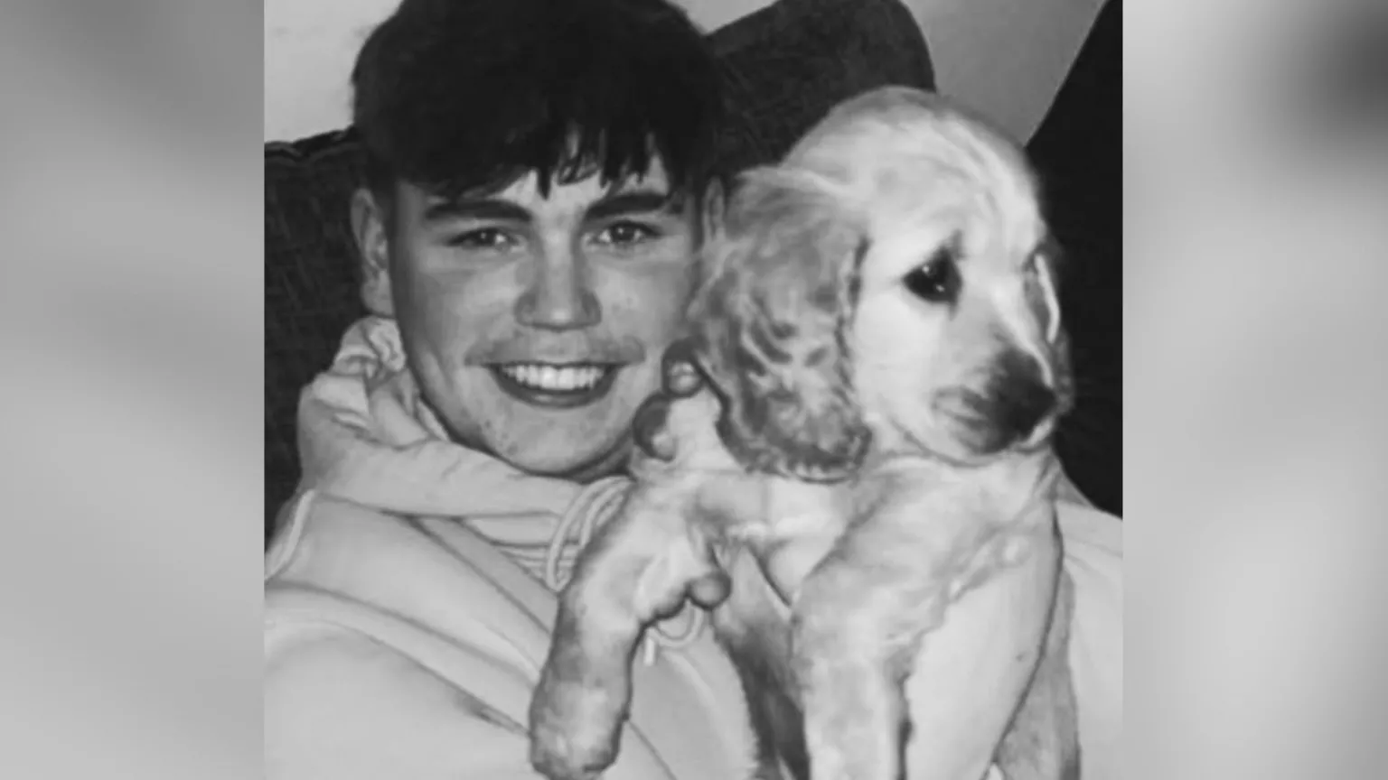 Family handout A black and white image of a young man with dark hair holding a puppy dog with floppy ears