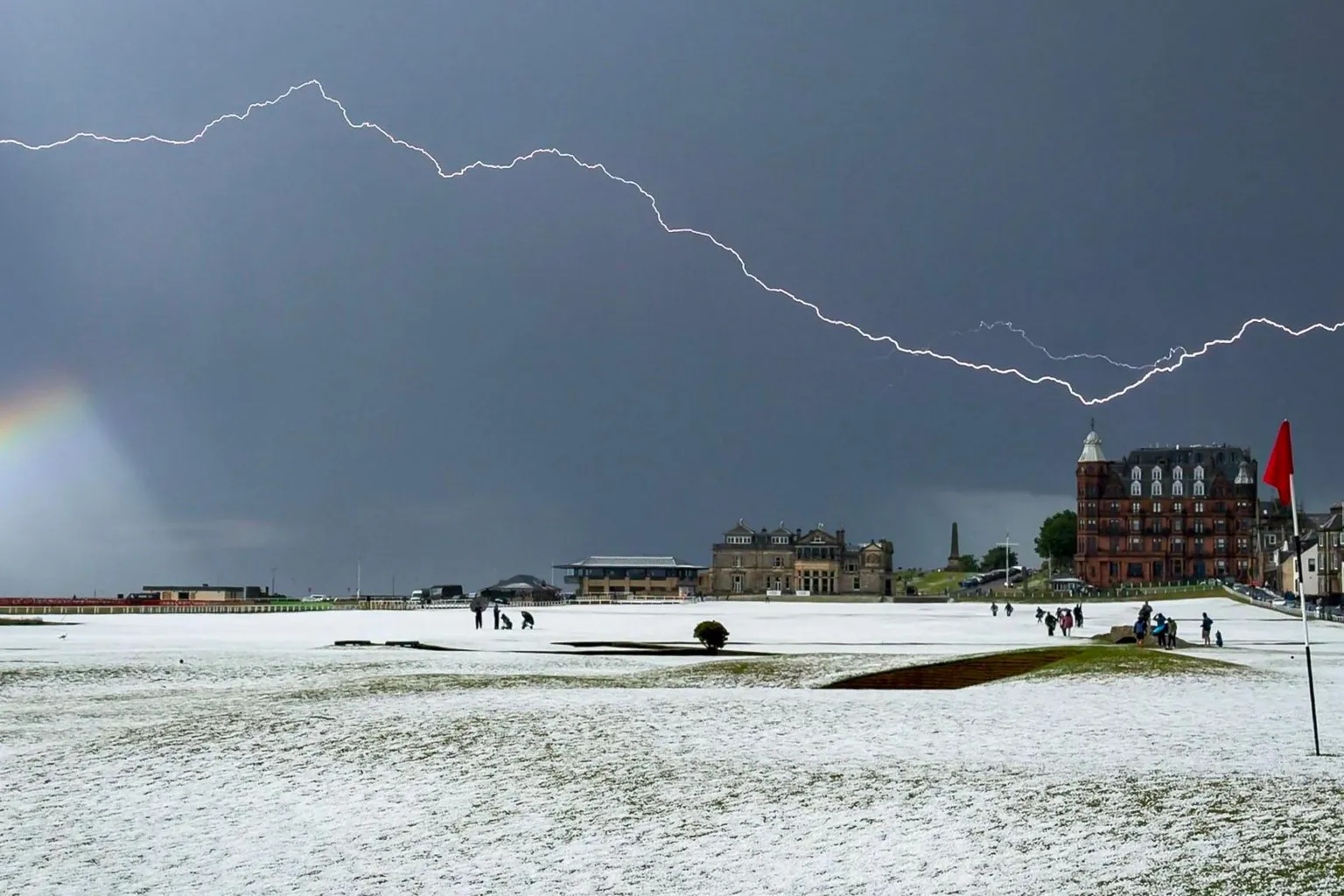Glen Gardiner A golf course is covered with snow and hail. A flash of lightning illuminates the sky.