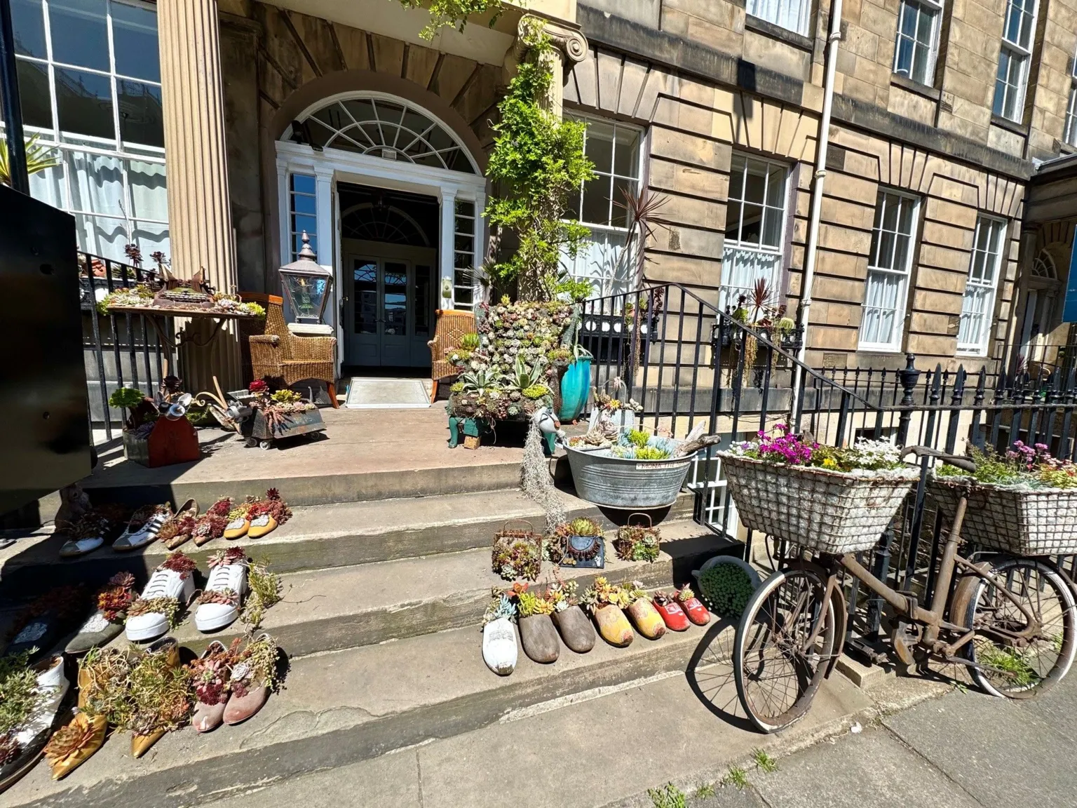 Lorna Donaldson An Edinburgh street with a variety of plants and flowers, contained in flowerpots that look like shoes.