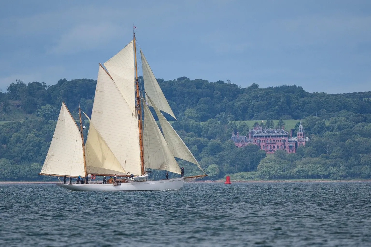 Jack de Koning A yacht sailing along, with a house visible on the shore in the distance