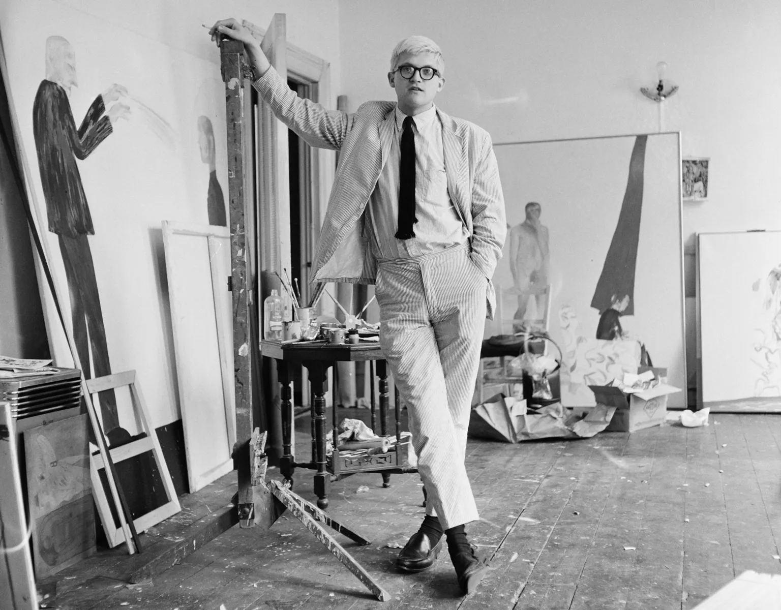 English artist David Hockney in a studio with some of his work, circa 1967.