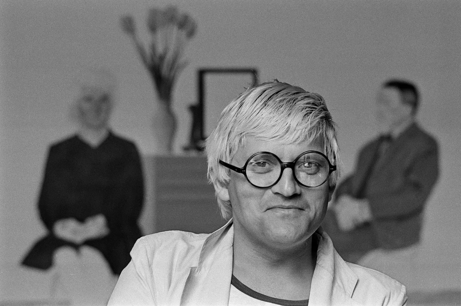 Portrait of English artist David Hockney in his Saint Germain studio, Paris, France, 1979. Partially visible behind him a version of his painting, 'My Parents and Myself,'