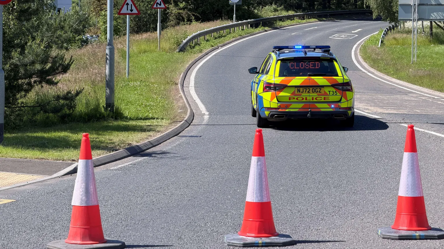 Mark Denten/BBC Orange-and-white traffic cones blocking off the A189 at Cramlington. A police car has an LED sign in its rear window spelling out the word 
