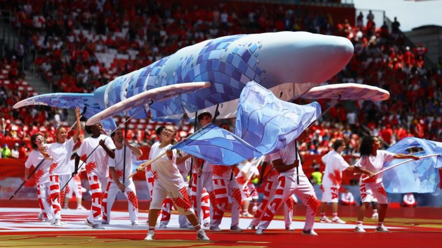 A whale puppet being held up by performers
